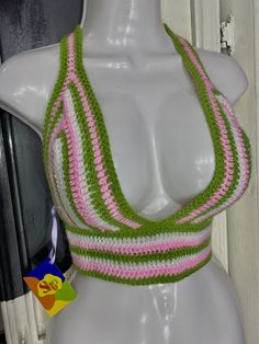 a white mannequin wearing a green and pink crocheted halter top