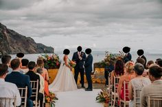 a bride and groom standing at the end of their wedding ceremony in front of an ocean view