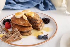 a plate topped with pancakes covered in bananas and berries