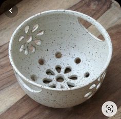 a white bowl sitting on top of a wooden table with holes in the bottom and sides