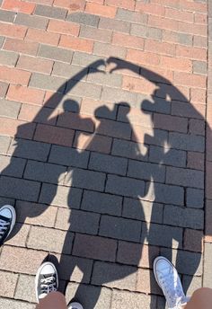 the shadow of two people standing next to each other on a brick walkway with their feet up