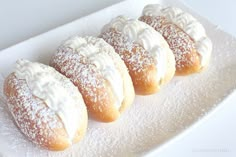 four pastries on a white plate with powdered sugar