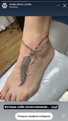 a woman's foot with a chain and feather tattoo on the side of her ankle