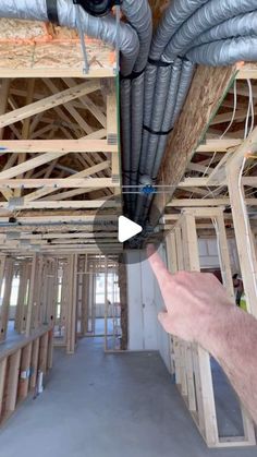 a person pointing at the ceiling in a house under construction with exposed pipes and piping