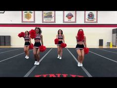 three cheerleaders in red pom poms are dancing on the gym floor