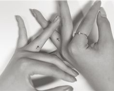 two hands holding each other with cross tattoos on their fingers