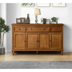 a wooden cabinet with drawers and pictures on the wall above it in a living room