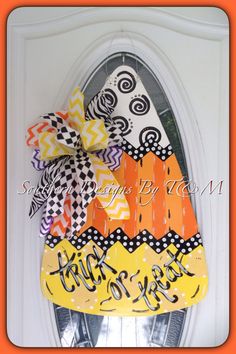 a door hanger decorated with an orange, yellow and black pumpkin