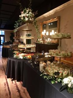 a long table with many plates and bowls on it in a room filled with flowers