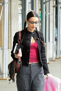 a woman walking down the street carrying a pink bag