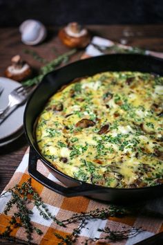 an omelet with mushrooms and parsley in a black pan on a checkered table cloth