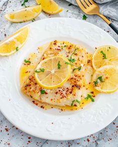 a white plate topped with fish covered in lemon slices