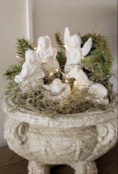 a white planter filled with angel figurines and lights