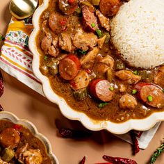 a white plate topped with meat and veggies covered in gravy next to rice