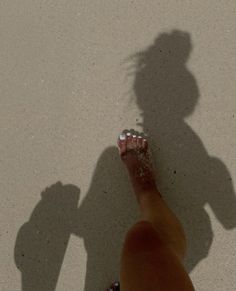 the shadow of a person standing next to a skateboard on cement ground with one foot in the air