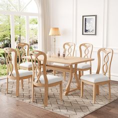 a dining room table with six chairs and a rug on the floor in front of it