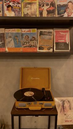 a record player sitting on top of a wooden table next to a shelf filled with books