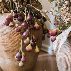 two vases filled with dried flowers on top of a wooden table next to each other