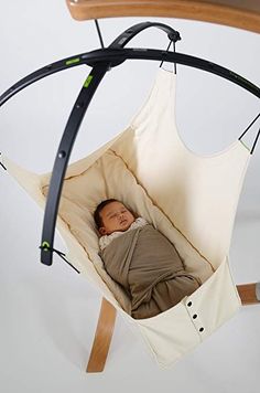 a baby is sleeping in a hammock hanging from a wooden frame with black straps