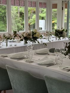 the table is set with white plates and silverware, flowers in vases, and wine glasses