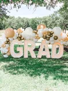 a large sign that says grad in gold and white balloons on top of it