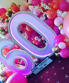 the number 50 is surrounded by balloons and streamers in pink, orange, and purple