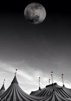 a full moon is seen above some circus tents