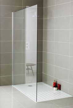 a bathroom with a walk in shower next to a red towel on the wall and two vases