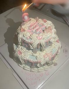 a birthday cake that is sitting on a table with a lit candle in the shape of a heart