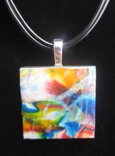 a square glass pendant is hanging on a black cord with a silver necklace attached to it