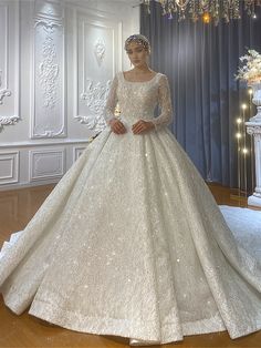 a woman in a white wedding dress standing on a wooden floor next to a chandelier