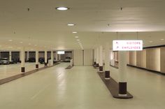 an empty parking garage filled with lots of parked cars and tall pillars in front of them