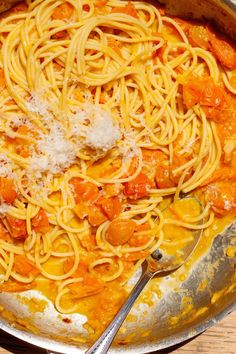 a pan filled with pasta and sauce on top of a wooden table