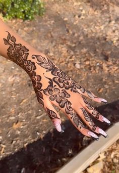 a woman's hand with hennap on it and some leaves in the background