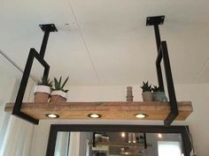 two potted plants sitting on top of a wooden shelf above a mirror in a room