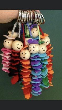 a hand holding a bunch of colorful items with smiley faces on them and other small objects attached to the strings