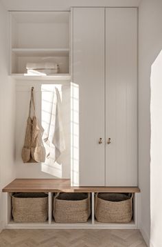 a white closet with baskets and towels hanging on the wall