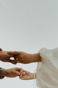 the bride and groom hold hands as they stand close to each other with their wedding rings