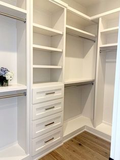 an empty walk in closet with white shelves and drawers on the bottom shelf, filled with flowers