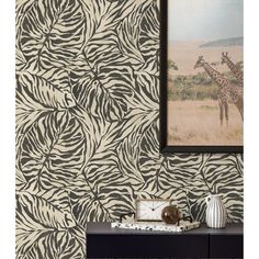 a giraffe and zebra print wallpaper in a room with a painting on the wall