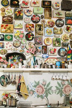 a wall covered with plates and pans next to a stove top oven in a kitchen