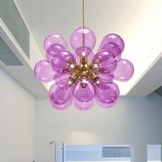 a purple chandelier hanging from the ceiling in a room with white walls and windows