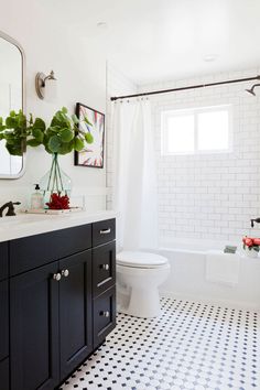 a bathroom with black and white tile flooring and walls, along with a large mirror on the wall