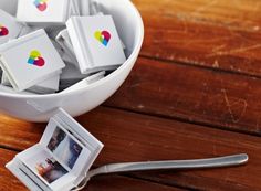 a bowl filled with small polaroid pictures next to an mp3 player