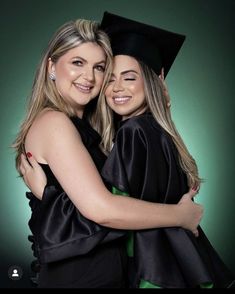 two women in graduation gowns hugging each other