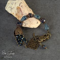 a bracelet with beads and charms on top of a rock next to a stone slab