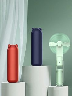 three different colored items on pedestals in front of a window