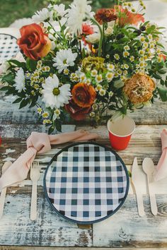 the table is set with flowers and utensils for an outdoor dinner or brunch