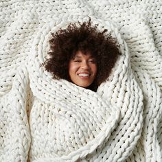 a smiling woman wrapped in a white blanket