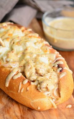 a hot dog covered in cheese on a wooden cutting board